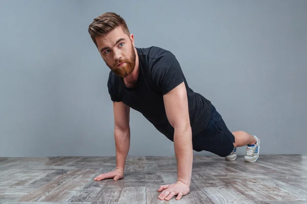 Serious bearded young sportsman doing plank core exercise