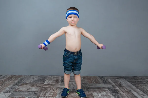 Cute little boy standing and working out using dumbbells — Stock Photo, Image