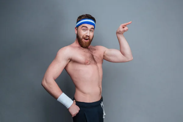 Komik sakallı genç sporcu uzağa işaret — Stok fotoğraf