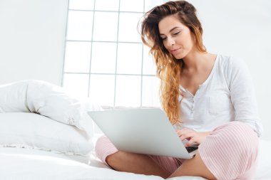 Yatağa dizüstü bilgisayar kullanan kadın