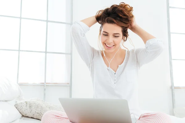 Frau benutzt Laptop auf dem Bett — Stockfoto