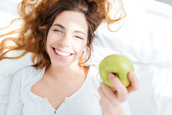 Frau hält Apfel auf dem Bett — Stockfoto