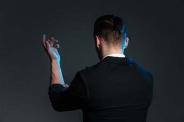 Back view of young man magician standing with raised hand clipart