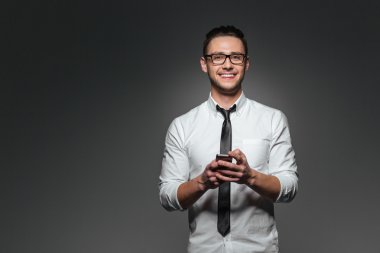 Mutlu genç işadamı ayakta ve akıllı telefon kullanarak