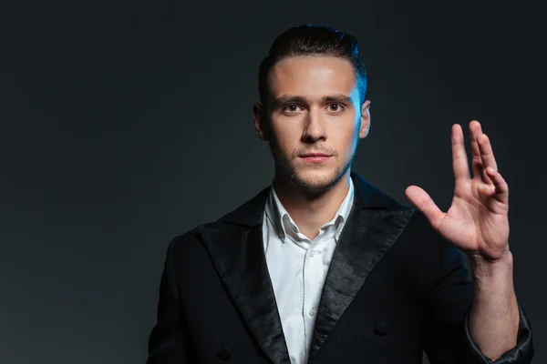 Portrait of confident young man magician with raised hand — Stock Photo, Image