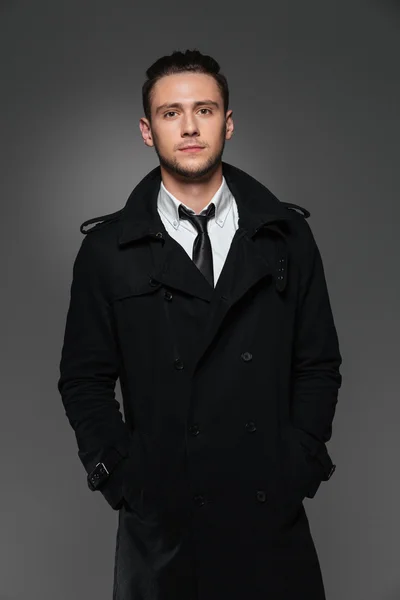 Portrait of confident handsome young businessman in black coat — Stock Photo, Image