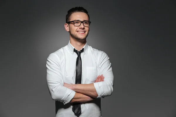 Sorridente giovane uomo d'affari con gli occhiali in piedi con le braccia incrociate — Foto Stock