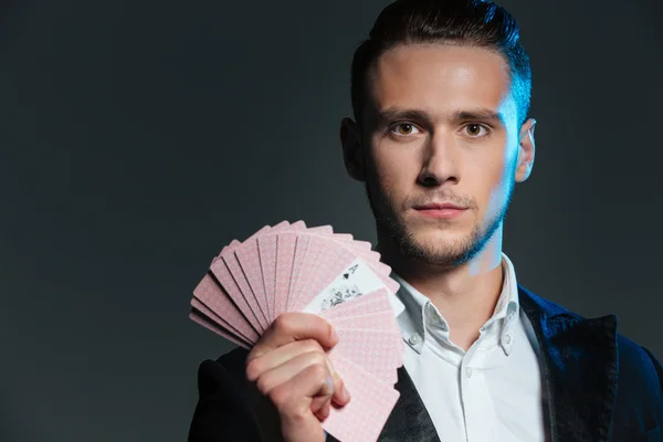 Allvarlig ung man magikern håller spelkort med ess — Stockfoto