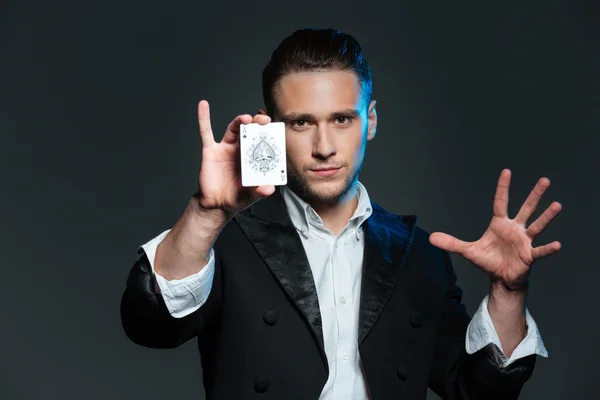 Jovem mágico confiante mostrando cartão ace — Fotografia de Stock