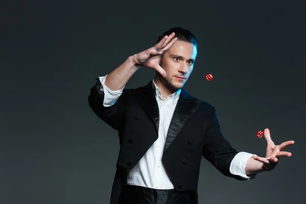 Handsome young man magician showing tricks with flying dice — Stock Photo, Image