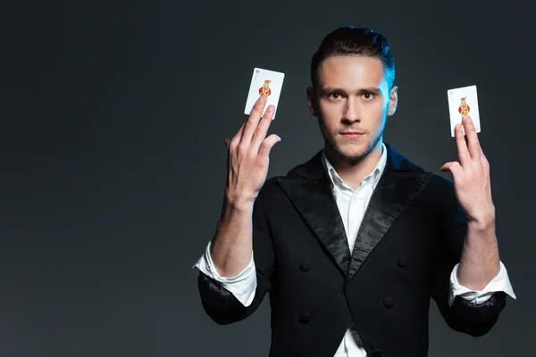 Jovem mágico atraente mostrando dois cartões jocker — Fotografia de Stock