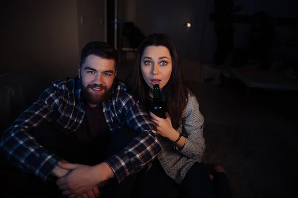 Happy young couple sitting and watching tv in dark room — Stock Photo, Image