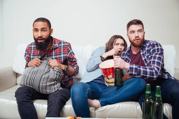 Przestraszony przyjaciółmi siedząc na kanapie i oglądać telewizję — Zdjęcie stockowe