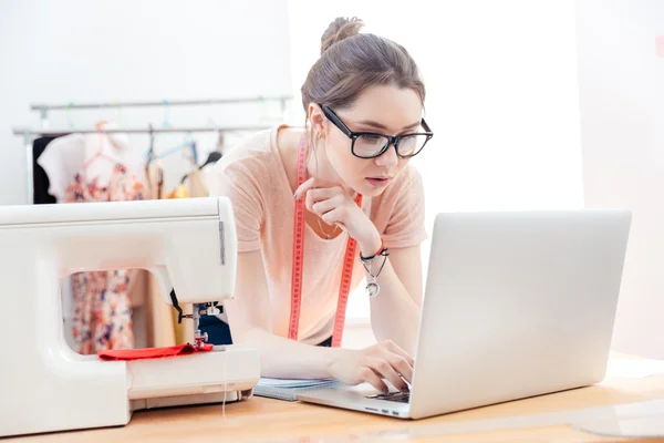 Serious woman seamstress using laptop in studio — Stock Photo, Image