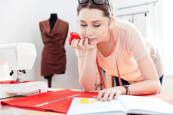 Cucitrice donna concentrata con motivo e disegno su tessuto rosso — Foto Stock