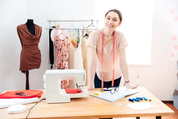 Smiling woman fashion designer standing and working in studio — Stock Photo, Image