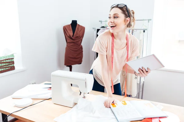 Cheerful woman seamstress with laptop at work — Stock Photo, Image