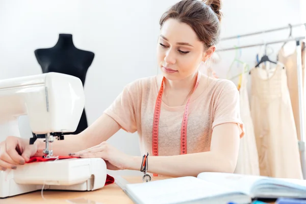 Concentrated woman seamstress sews on sewing machine — Stock Photo, Image