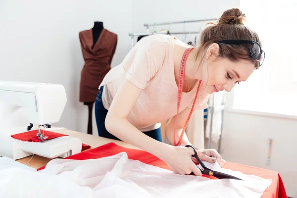 Mujer enfocada diseñador de moda corte de tela blanca en el estudio —  Fotos de Stock