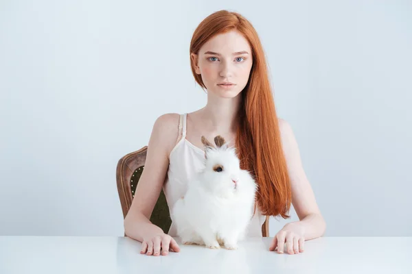 Mujer sentada a la mesa con conejo — Foto de Stock