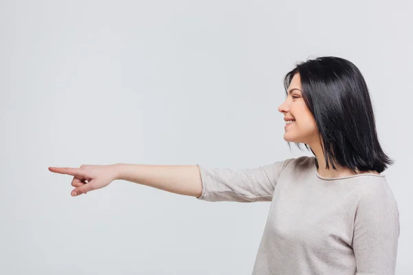 Lässige junge Frau zeigt mit dem Finger zur Seite — Stockfoto