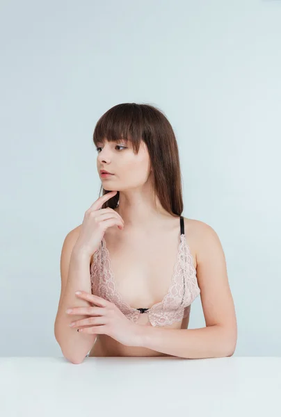 Mooie vrouw in lingerie zitten aan de tafel — Stockfoto