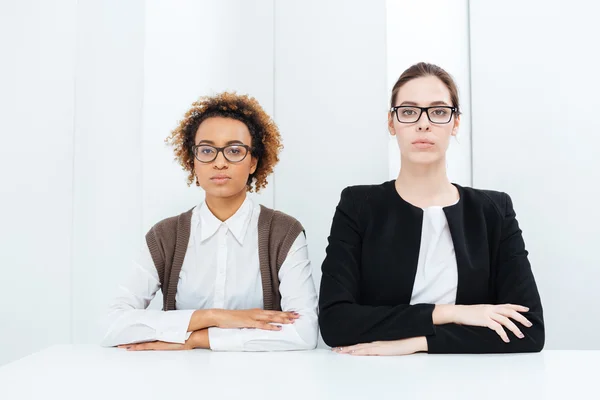 Två allvarliga unga busimesskvinnor i glasögon sittande raka — Stockfoto