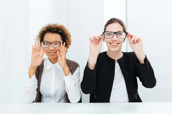 Две счастливые деловые женщины веселятся в очках в офисе — стоковое фото