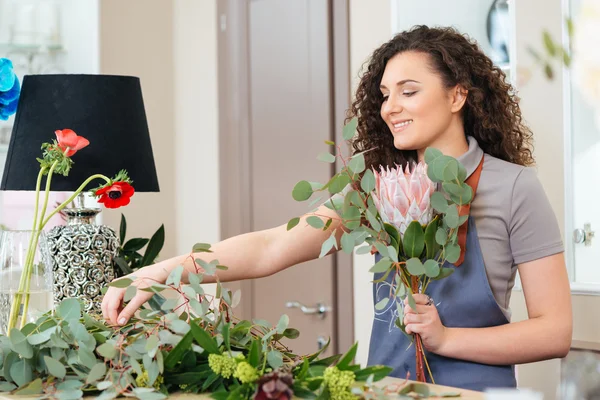 Щаслива жінка флорист робить букет на столі в магазині — стокове фото