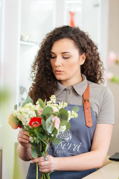 Focada florista mulher trabalhando e fazendo buquê de flores na loja — Fotografia de Stock