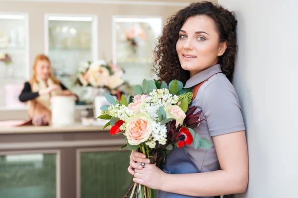 Mulher florista com buquê de flores de pé na loja de flores — Fotografia de Stock