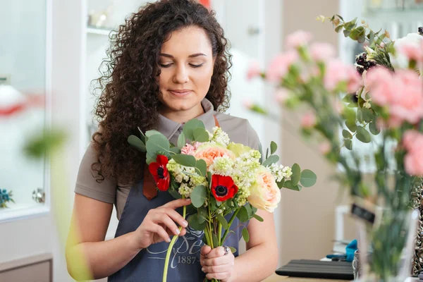 Mulher pensativa florista segurando flores e fazendo buquê na loja — Fotografia de Stock