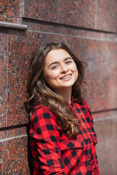 Lächelnde, lässig an die Wand gelehnte Frau — Stockfoto