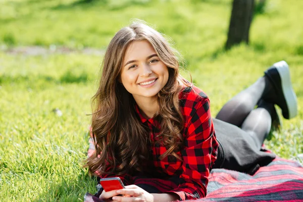 Frau liegt im Gras und blickt in Kamera — Stockfoto