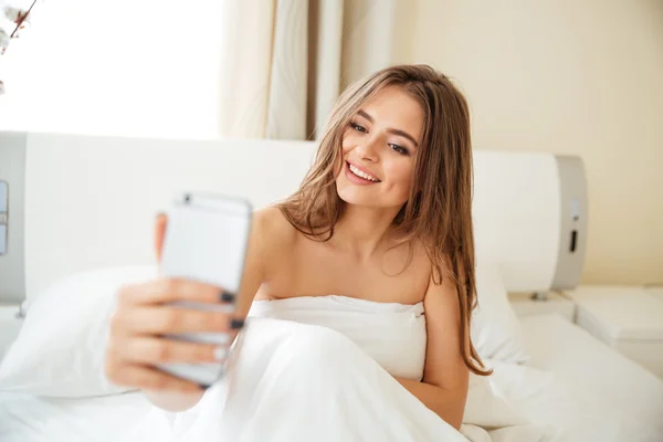 Mujer haciendo foto selfie en la cama en casa —  Fotos de Stock