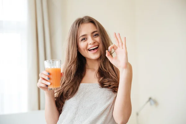 Mujer sosteniendo vaso con jugo de naranja y mostrando el pulgar hacia arriba — Foto de Stock