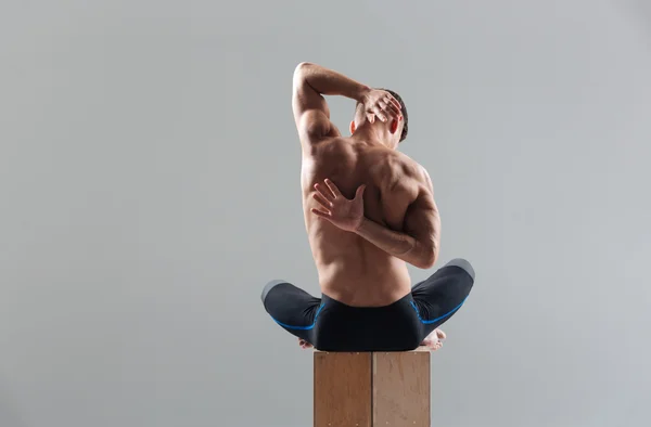 Fitness homme assis sur la boîte en bois et les mains tendues — Photo