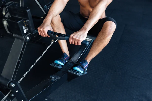 Gespierde fitness man met roei-machine in de sportschool — Stockfoto