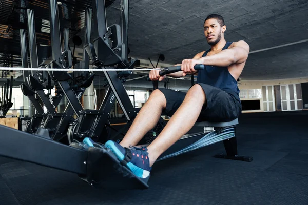 Człowiek fitness przy użyciu maszyny do wiosłowania w siłowni — Zdjęcie stockowe