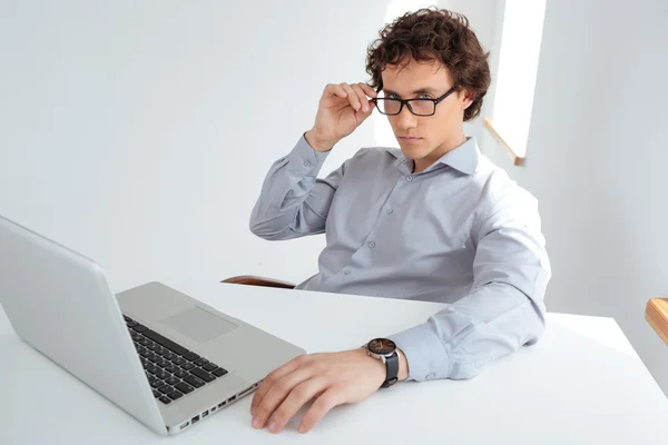 Uomo d'affari con gli occhiali seduto sul posto di lavoro — Foto Stock