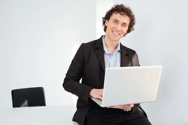 Empresário inclinado sobre a mesa com computador portátil — Fotografia de Stock