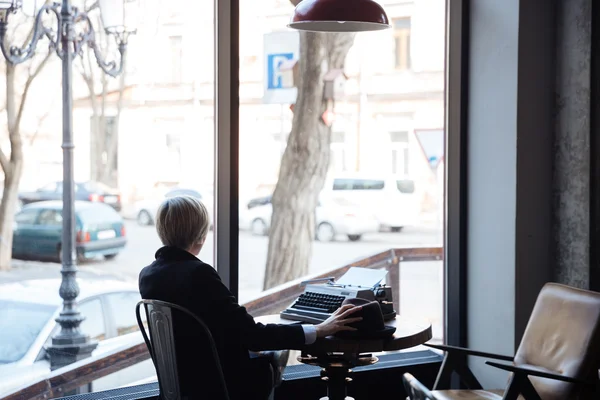 Blonde girl sitting backwards in a cafe — Stock Photo, Image