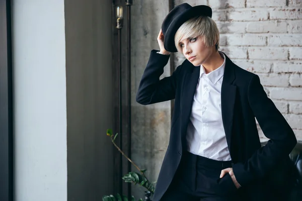 Beautiful blonde girl putting on a hat — Stock Photo, Image