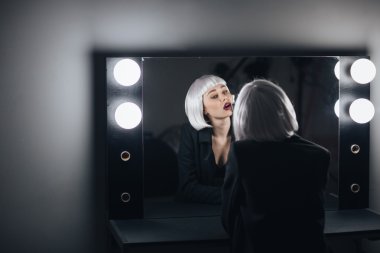 Baştan çıkarıcı sarışın kadın şampanya içme ve aynaya bakarak 