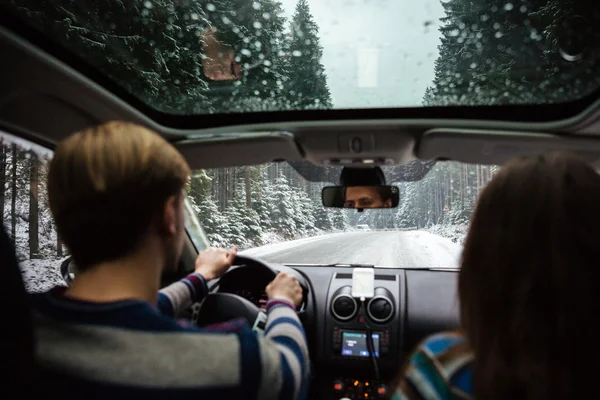 Hermosa pareja conduciendo en coche a través del bosque de invierno —  Fotos de Stock