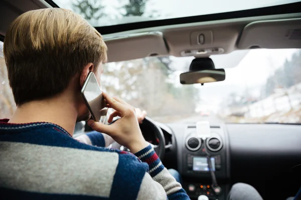 Man in striped sweater driving and talking on mobile phone — Stock Photo, Image
