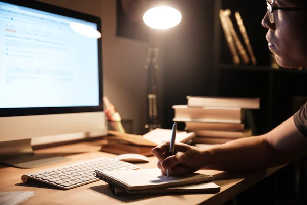 Hombre sentado y estudiando con computadora en casa por la noche — Foto de Stock