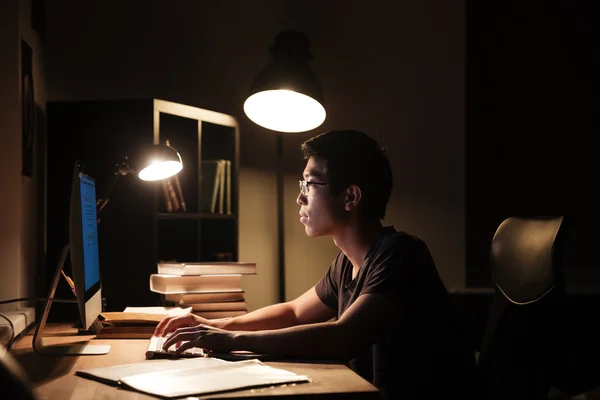 Hombre serio usando la computadora y escribiendo en el cuarto oscuro — Foto de Stock