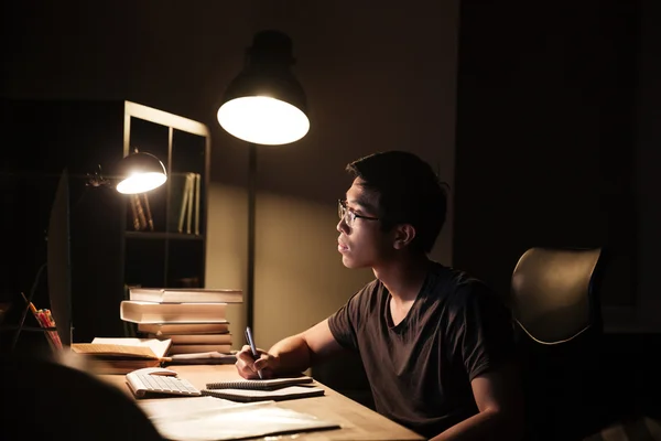 Концентрований чоловік використовує комп'ютер для вивчення та запису в блокноті — стокове фото