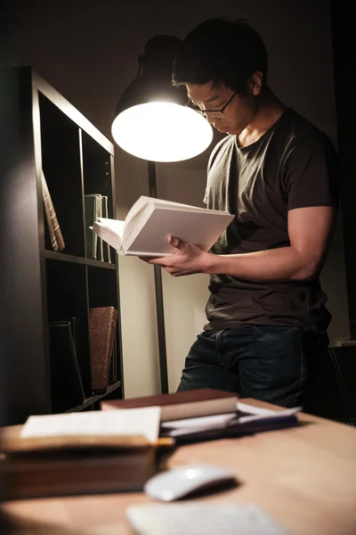 Atrakcyjny człowiek stojący i czytanie książki wieczorem — Zdjęcie stockowe